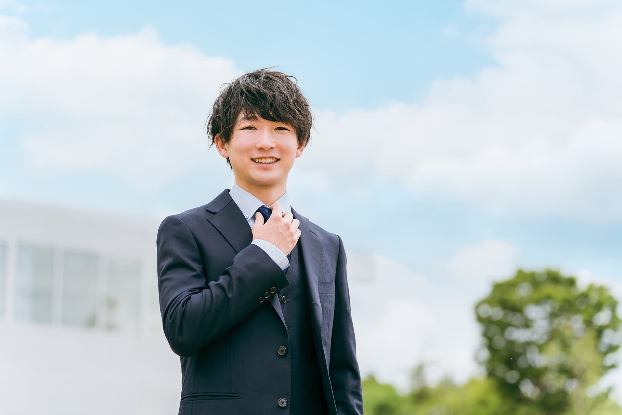 バルコニーで腕を組むスーツ姿の学生